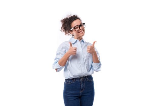 smart stylish young brunette curly employee of the company woman dressed in a light blue shirt on the background with copy space.