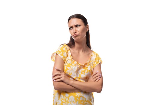 brunette young woman dressed in a summer yellow outfit makes a grimace and displeasure.
