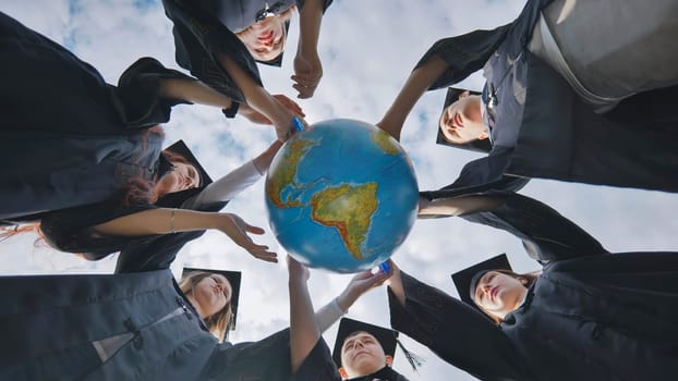 Graduating students spin a geographical globe of the world