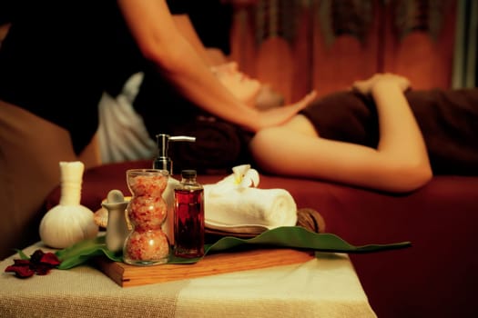 Aromatherapy massage ambiance or spa salon composition setup with focus decor candles and spa accessories on blur couple enjoying blissful aroma spa massage in resort or hotel background. Quiescent