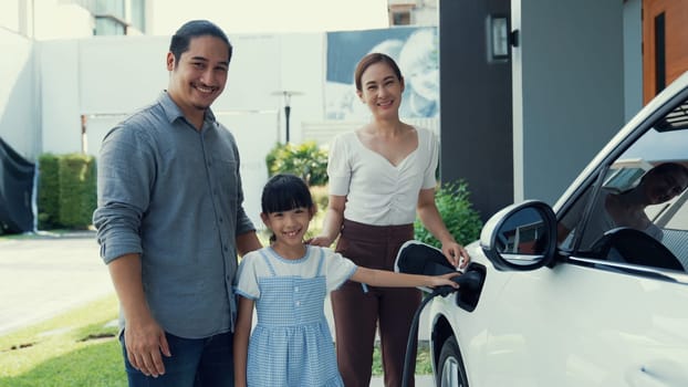 Concept of a progressive family with a home charging station for an electric vehicle, encouraging healthy and clean environment. The electric vehicle powered by sustainable, clean energy technology.