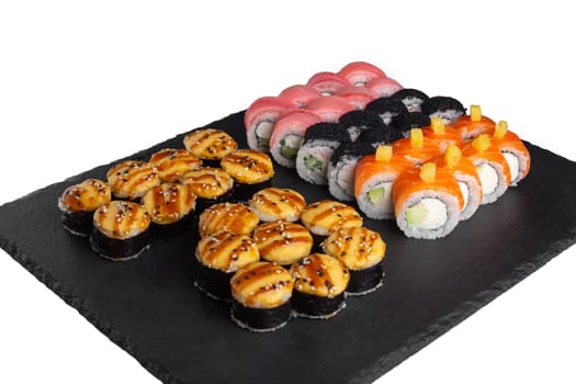 Sushi set with ginger and wasabi on a slate plate isolated on white background. Five types of rolls in one set.