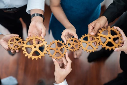 Office worker holding cog wheel as unity and teamwork in corporate workplace concept. Diverse colleague business people showing symbol of visionary system and mechanism for business success. Concord