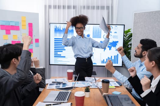 Business people celebrate after successful presentation or meeting on data analysis display on TV screen. Happy team gathers in office room, cheer to collaboration with celebratory gesture. Concord