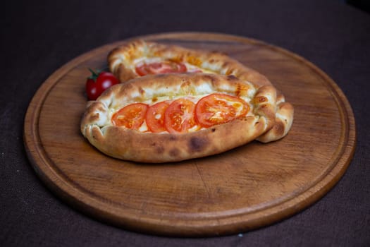 khachapuri recipe with tomatoes. khachapuri on a wooden plate.