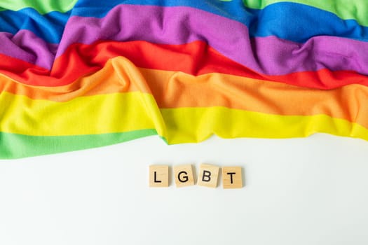 Rainbow flag, a symbol of the LGBT community, on the background of the inscription in wooden letters LGBT