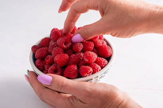 fresh raspberries in a bowl in woman hands, summer harvest fruits and fresh berries, vitamins, vegetarian concept, High quality photo