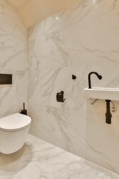 a bathroom with marble walls and white fixtures on the wall, there is a toilet in the corner next to the sink