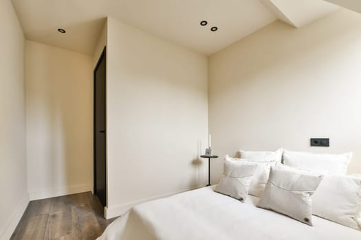 a bedroom with white bedding and wood flooring in front of the door to the room is very light