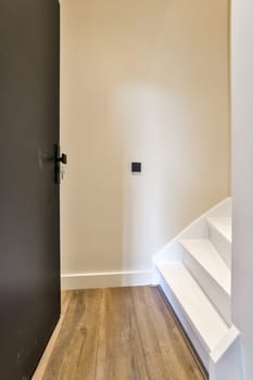 an empty room with wood flooring and white paint on the walls, there is a black door in the corner