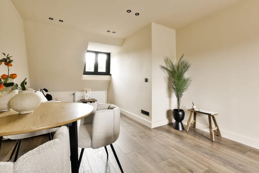 a dining table and chairs in a room with white walls, wood flooring and an orange vase on the table