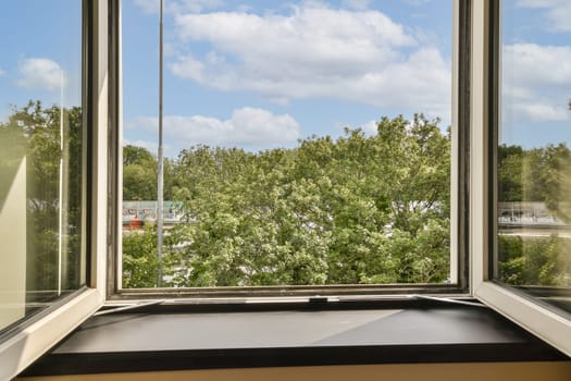 an outside view from a window with white clouds in the sky and green trees on the other side of the window