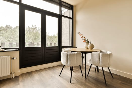 a dining room with two chairs and a small table in front of the window that looks out onto the street