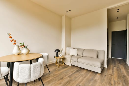 a living room with wood flooring and white sofas in the center of the room is a black door