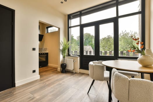 a living room with wood flooring and large windows looking out onto the trees in the view from the dining area