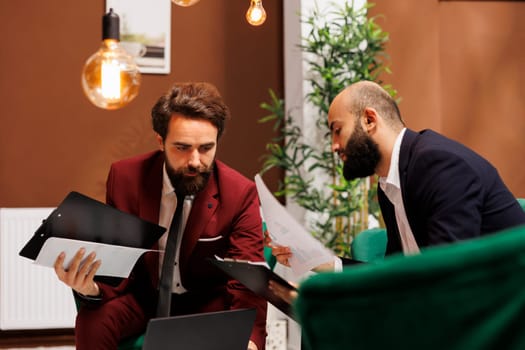 Male travellers attending meeting abroad to share experiences, discovering new corporate perspectives and ways of doing business. Colleagues in suits exchanging cultural ideas in hotel.