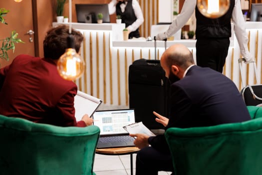 Busnessmen sharing ideas at hotel, meeting in lounge area lobby to forge new corporate partnership. People in suits discussing about management project at important conference, travelling for work.