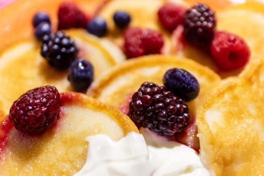 Close-up delicious pancakes, with fresh blueberries, raspberries and blackberries, the background of a delicious dessert