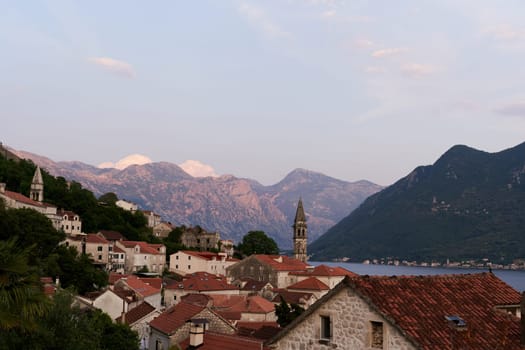 View over the roofs of old houses on the bell tower of the church on the seashore. Perast, Montenegro. High quality photo