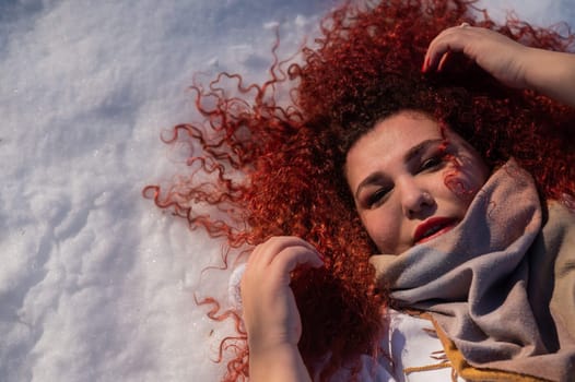 Top view of a fat red-haired woman lying on the snow