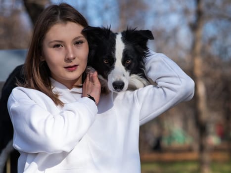 Caucasian woman hugging her dog Border Collie while sitting on a bench in autumn park