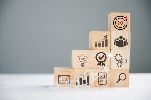 Business target concept with a wooden cube block step. Action Plan and Goal icons symbolize success. Project management and company strategy on a table. Teamwork background.