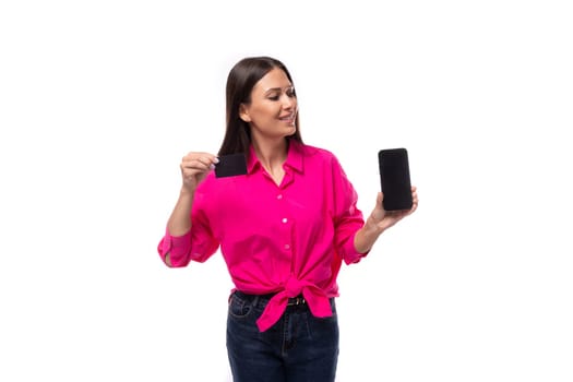 charming young brunette businesswoman dressed in a pink shirt shows the smartphone screen.