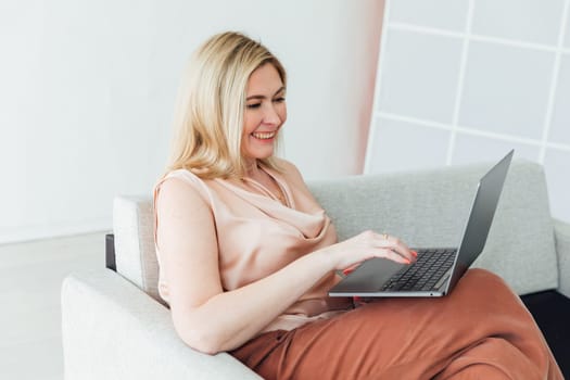 Shot of a middle aged woman using her laptop on the sofa at home.