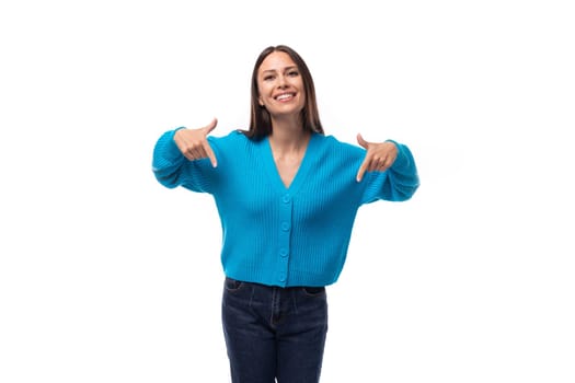 young pretty smiling brunette promoter woman in a blue cardigan actively gesturing with her hands on a white background.