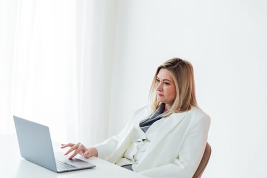 40s mid age European business woman CEO using laptop application for work sitting at table workspace in office. Smiling Latin Hispanic mature adult professional businesswoman using pc digital computer