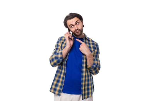 a young caucasian brutal man with an unshaven face dressed in a blue plaid shirt speaks on the phone.