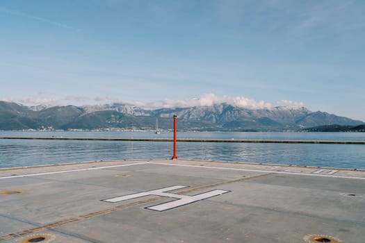 Helipad on the pier with a signal beacon by the sea against the backdrop of the mountains. High quality photo