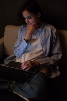 Woman sitting on sofa with computer chatting online