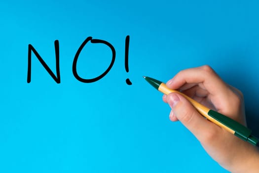 Children hand with pen write on a blue white background. Writing hand. Word NO