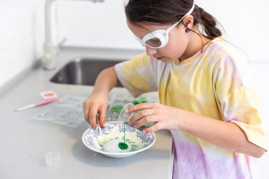 Enthusiastic little girl doing home science project, having a eureka moment. She has chemistry glassware with colorful liquids.