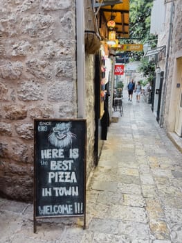 Signboard of a pizzeria drawn in chalk on a slate board next to an old building. High quality photo