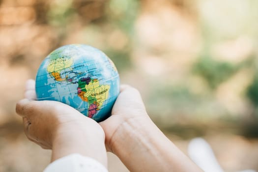 Celebrate World Earth Day with the concept of Green Energy, ESG, and Sustainable Resources. Hold a green leaf and the globe in your hand to signify responsibility and environmental care.