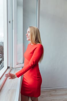 a beautiful blonde woman standing at the window in the room