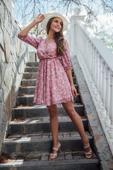 a beautiful woman in a hat standing on the stairs on the street walk