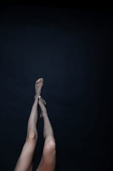 women's slender legs in mesh tights on black background