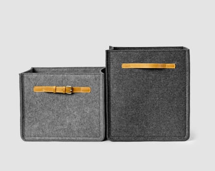 Two gray storage boxes made of natural felt with leather handles and buckles. Stylish artisanal accessories to organize wardrobe or workplace