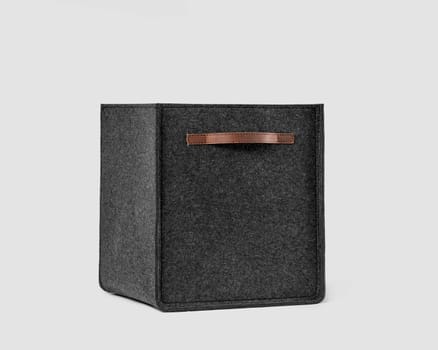 Multifunctional storage basket made of natural gray felt with brown leather handles for organizing office space, keeping papers and folders. Artisanal interior accessory