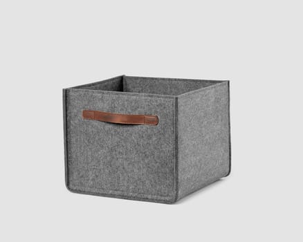 Functional storage box of natural gray felt with brown leather handles for carrying and storing things in home and office. Artisanal accessories for interior design