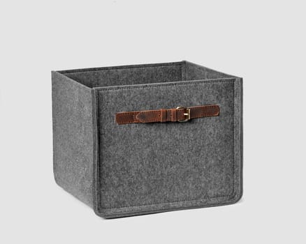 Functional storage box of natural gray felt with leather handles for carrying and storing things in modern home space. Artisanal accessories for interior design