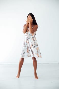a brunette woman in a floral dress covers her face with her hands I can't see