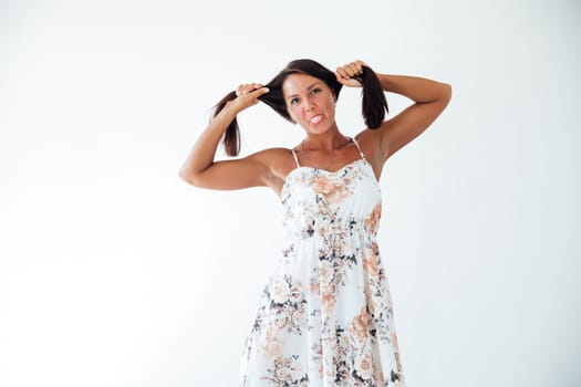 woman in a floral dress holds her hair with her hands