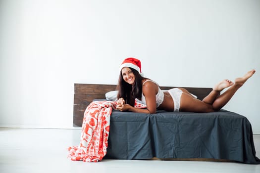 woman in underwear in a Christmas cap lies on the bed in the bedroom