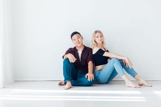 man and a woman couple sit against a light wall