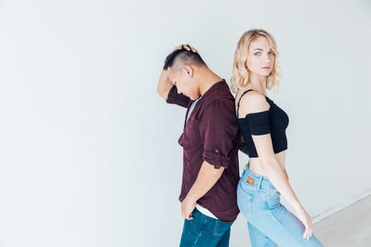 man and a woman couple stand back to back in a bright room