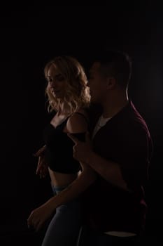 man and a woman in love dance in a dark hall